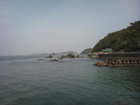 夫婦岩。山の麓に見えるのは二見興玉神社（ふたみ　おきたまじんじゃ）