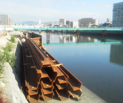 これは，猿候川東大橋の架け替え工事の進捗状況です．青い仮設橋の手前にあった旧橋脚がすっかりなくなり，鋼矢板がずらっと控えています．