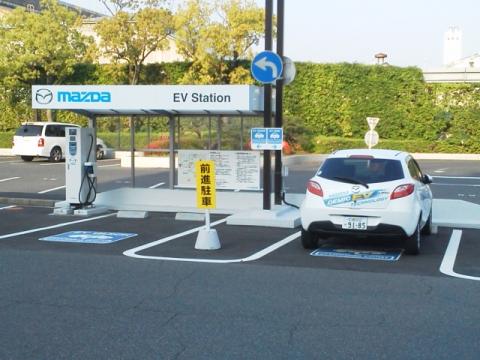 ここは,マツダの来客用駐車場に設けられたEVステーション,電気自動車の充電ステーションです.停まっているのはデミオの電気自動車です.この車の製造コストは・・・