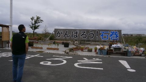 日和山公園を降りた海岸沿いの門脇町にある　がんばろう！石巻　の看板の前に佇むとのさん